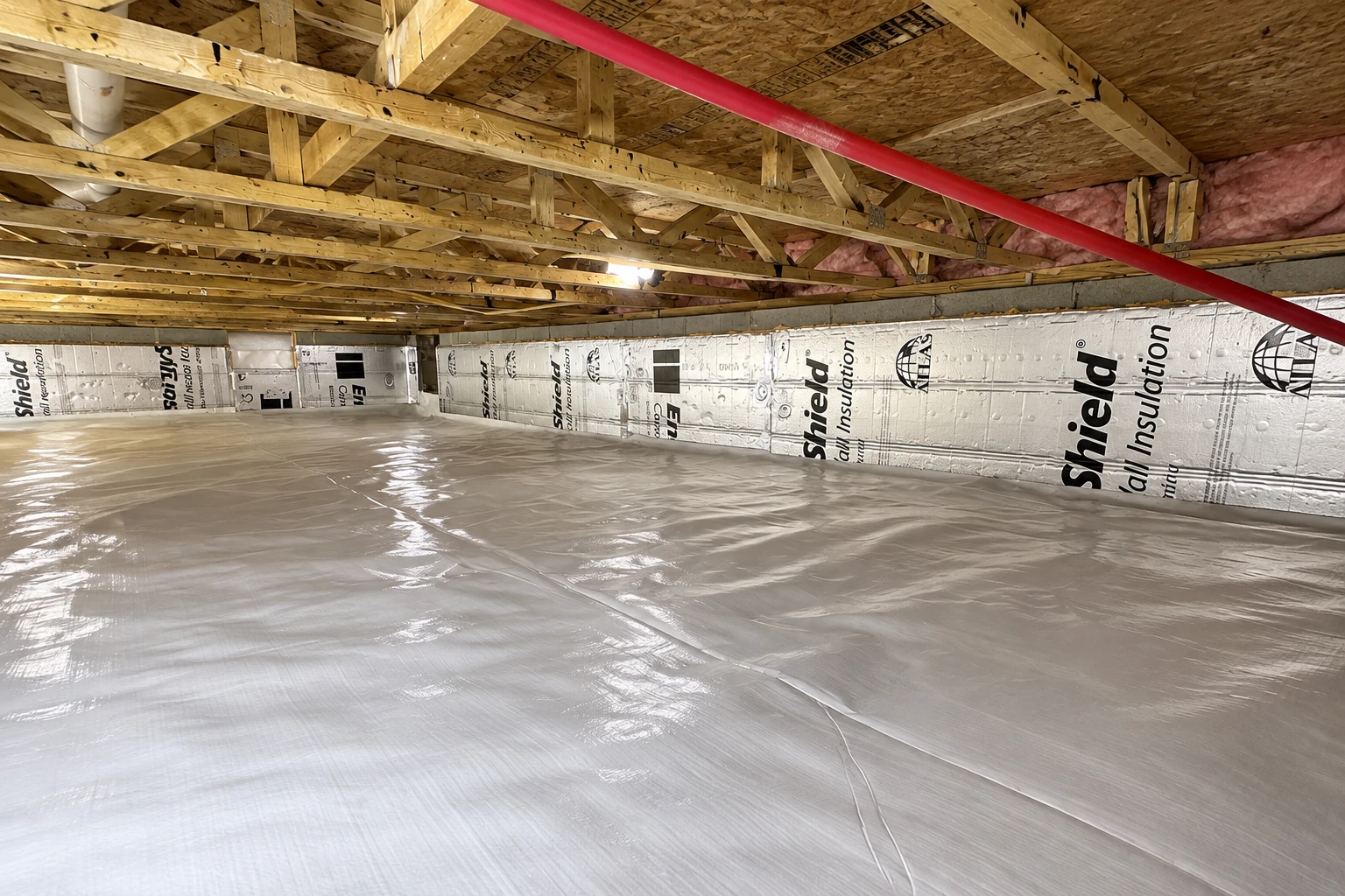 Crawl space with a reflective plastic vapor barrier covering the floor and rigid insulation panels lining the walls.